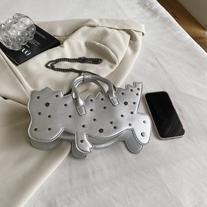 Chic silver dinosaur-shaped handbag with metallic studs and chain strap on neutral fabric