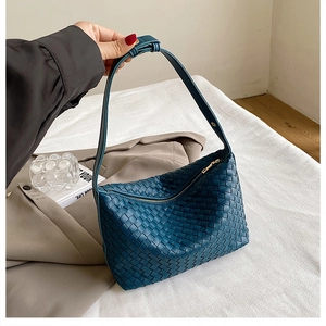 Close-up of teal woven leather texture and metal zipper on a luxury hobo shoulder bag