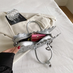 Detail of silver dinosaur shaped handbag with metal chain and pink interior storage