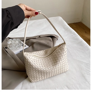 Detailed view of the off-white woven faux leather texture and top handle of the hobo bag