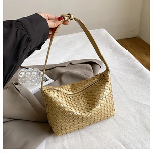 Detailed view of woven leather texture on champagne gold underarm bag with zipper