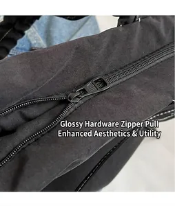 Detail of smooth metal zipper head on black pleated tote bag with white decorative stitching