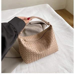 Close-up of beige woven leather hobo bag texture with elegant minimalist handle detail