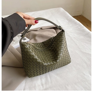 Detail of dark green woven leather handbag with gold zipper and premium texture