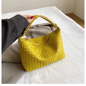 Macro detail of the yellow woven leather texture and metal zipper on the shoulder bag