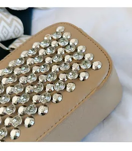 Close-up of sparkling rhinestones and textured PU leather on a beige shoulder bag