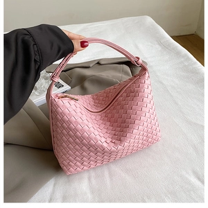 Close-up of pink woven leather texture with gold zipper on a stylish hobo bag