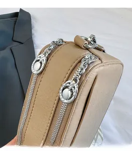 Detail of camera bag dual zippers with decorative metal pullers and woven strap