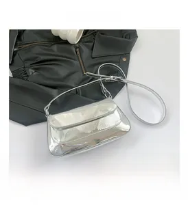Detail view of silver mirror PU leather shoulder bag on a black jacket background