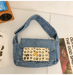 Detail view of vintage blue denim shoulder bag with metal studs and flap closure design