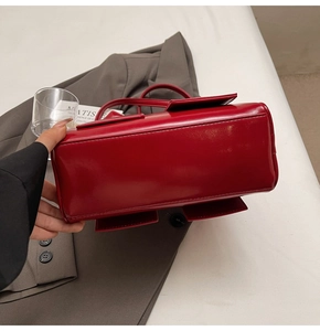 Detail view of the rectangular bottom and stitching on a red patent leather tote bag