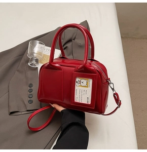 Detail of red patent leather tote bag with transparent card slot and dog illustration
