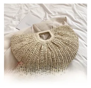 Detailed view of handmade woven straw moon bag on white bedding with summer holiday vibe
