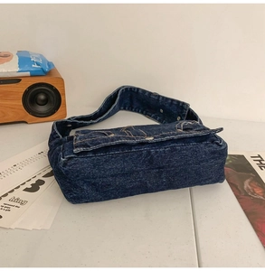 Detail of vintage washed denim shoulder bag featuring yellow contrast stitching and flap