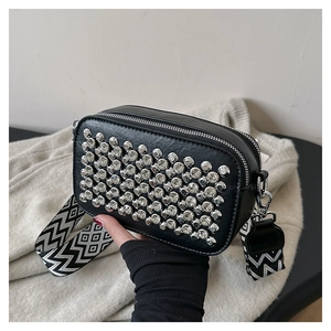 Close-up of sparkling silver rhinestones on black crossbody camera bag with wavy strap
