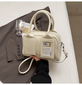 Detail of cream leather boston bag with transparent card slot and bear decorative card