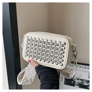Detail of a beige rhinestone crossbody bag with silver hardware and woven strap