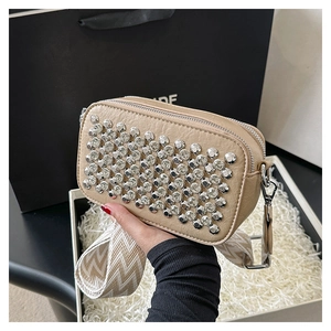 Close-up of khaki leather camera bag with silver stud accents and dual zipper detail