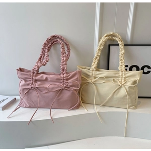 Detail van nylon schoudertassen met geplooide handvaten en strikjes in roze en beige