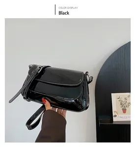 Detail of glossy black patent leather shoulder bag featuring silver metal buckle strap