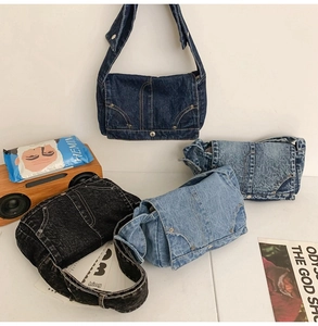 Detail view of denim messenger bags in four washes featuring utility pockets and stitching