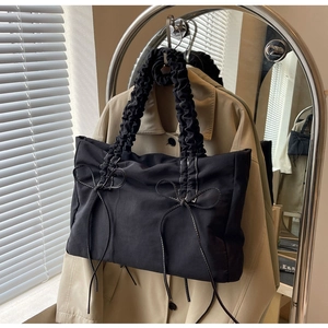 Detail van zwarte nylon draagtas met geplooide handvatten en stijlvolle witte strikken