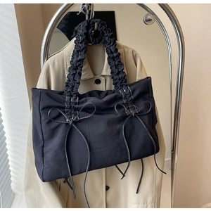 Detail van nylon draagtas met witte strikstiksels en geplooid scrunchie-handvat