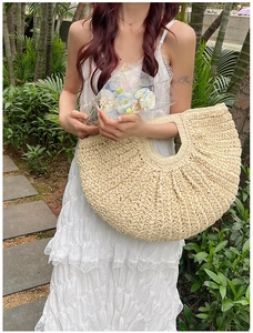 Close-up of crescent straw tote bag showing dense handmade woven texture and handle