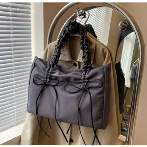Detail van donkergrijze nylon draagtas met geplooide handgreep en zwarte lintstrikken