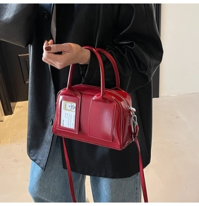 Detail of red patent leather Boston bag with clear card slot and silver hardware accents