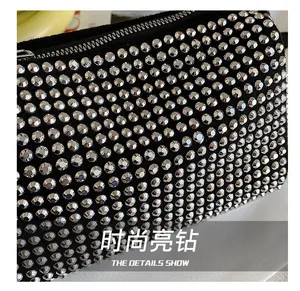 Macro shot of silver rhinestones on black fabric with metallic zipper on the handbag