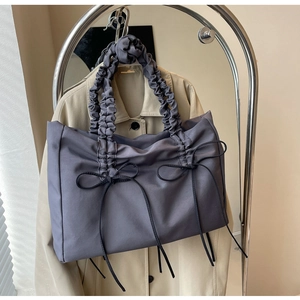 Detail van donkerpaarse nylon draagtas met zwarte strikken en geplooide handgreep
