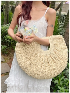 Detail of straw woven handbag with fan-shaped pleated texture in natural beige