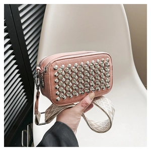 Detail of light pink crossbody bag with silver studs and geometric pattern wide strap