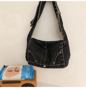 Detail of vintage washed black denim bag featuring metallic rivets and wide strap