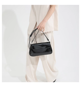 Macro shot of glossy black patent leather shoulder bag with sleek rectangular flap design