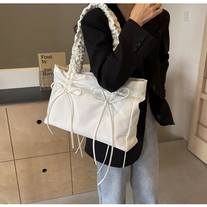 Detail van de witte nylon draagtas met scrunchie handvatten en subtiele strikjes