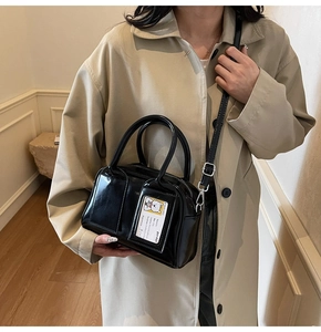 Detail of black glossy faux leather tote bag with transparent card slot and bear card