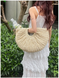 Detail of a large bohemian crescent straw handbag paired with a white lace dress for vacation