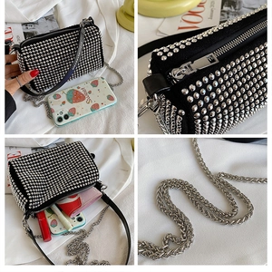 Detail view of black cylinder bag featuring silver studs, chain strap, and interior space