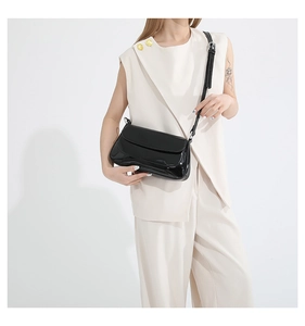 Detail of black glossy patent leather crossbody bag with adjustable shoulder strap