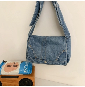 Detail of denim shoulder bag featuring classic jeans pocket design with orange stitching