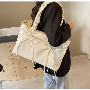 Detail van gebroken witte geplooide shopper met strikken en een gerimpelde schouderband