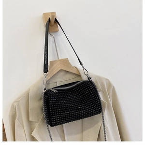 Detail of a black rhinestone cylinder bag with metallic chain and lettered strap