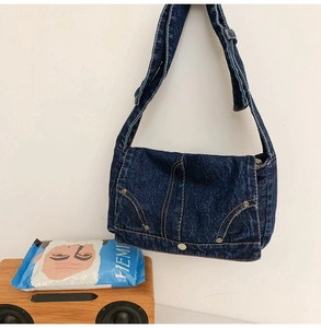 Detailed macro of vintage washed blue denim crossbody bag with contrast brown stitching