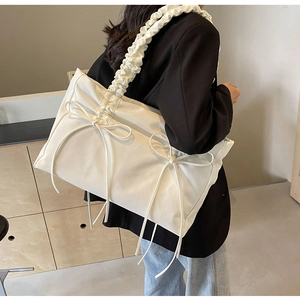 Detailopname van witte tote bag met geplooide schouderband en strikaccenten
