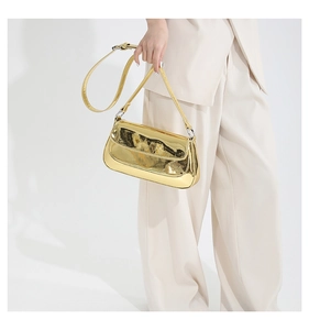 Model wearing a high-gloss gold metallic shoulder bag with a sleek minimalist silhouette