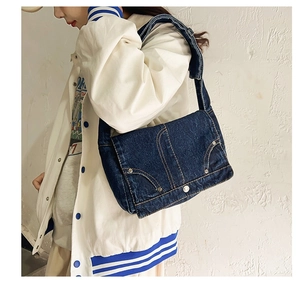 Detail of dark blue denim crossbody bag featuring vintage pocket design and stitching
