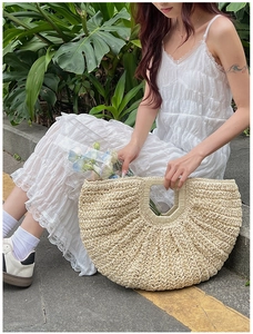 Close-up of beige straw tote bag featuring a fan-shaped silhouette and textured weave