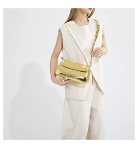 Glossy gold baguette shoulder bag with silver hardware on a model in beige suit